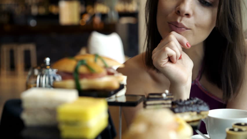 Beautiful woman eating tasty cake at cafe, 4K

