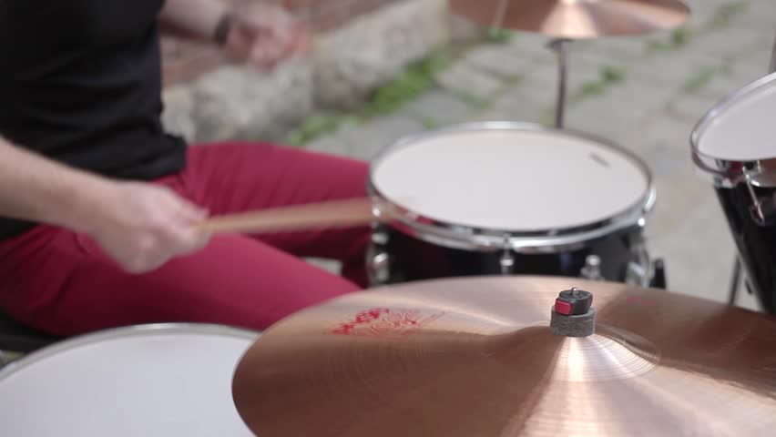 Man Playing Drums on the Street on the Background of a Brick Wall