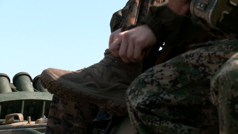 soldiers sitting on the armored vehicle checks the laces on the shoes