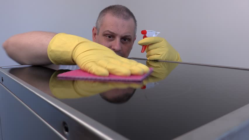 Worker cleaning surface of electric cooker close up