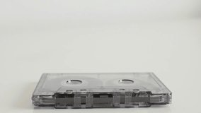 Transparent analogue magnetic tape close-up 4K 2160p 30fps UltraHD tilting footage - Retro compact audio cassette on white background  slow tilt 3840X2160 UHD video
