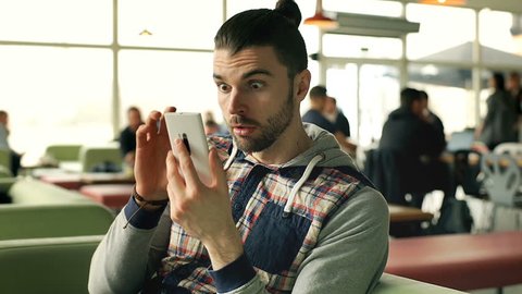 Man looks shocked while having received very bad news on smartphone, steadycam shot
