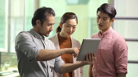 team of young asian business executives working together using digital tablet in office. 