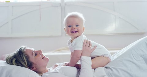 The best moments from life, a loving happy young mother hugs a nursing son, on a snow-white blanket, on a white background. concept of love, family, and happiness Concept: children, kids, baby, babies