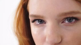 Close-up face of pretty young red haired girl with beautiful big blue eyes isolated over white