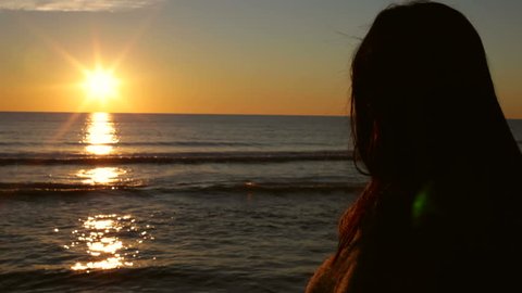 Silhouette of woman watching sunset in front of the ocea