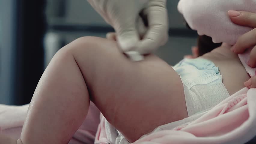 Close up shot: Doctor makes injection (leg muscle) to baby sitting in mothers arms Royalty-Free Stock Footage #25607354