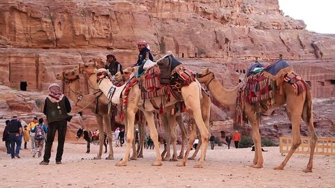 JORDAN, PETRA, DECEMBER 5, 2016: Jordanians on camels in Petra, originally known to Nabateans as Raqmu - historical and archaeological city in Hashemite Kingdom of Jordan