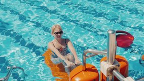 Attractive woman in a swimsuit doing exercises in the pool. Healthy lifestyle. Aqua aerobics in the open air