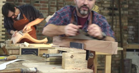 Cabinet-maker is preparing a detail for the table made of beech. In the background we see a young joiner polishing a cabriole table leg/Cabinet - Maker’s Handwork is Very Appreciated