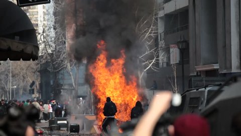 SANTIAGO, CHILE - AUGUST 9: Riot police disperse demonstrators who burned a car during a student strike on August 9, 2011 in Santiago, Chile.