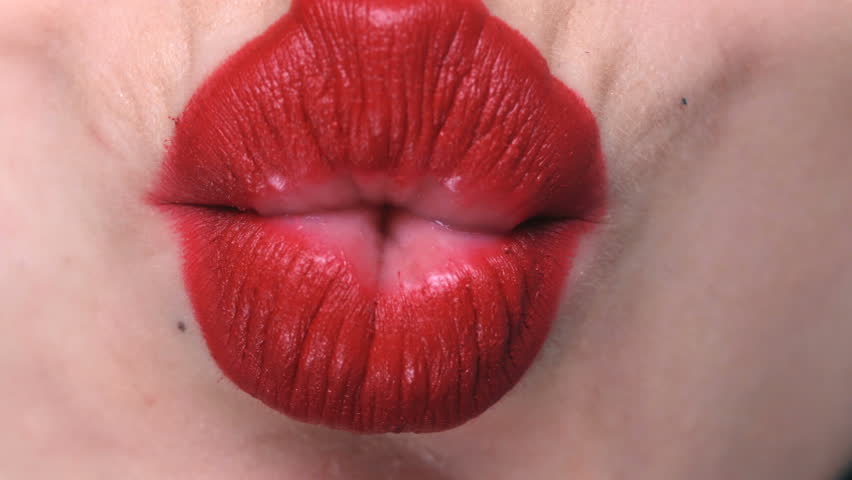Close up of a sensual female lips with red lipstick in kissing gesture Shut...