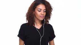 Happy young indian girl listening music with earphones and having fun dancing isolated over white
