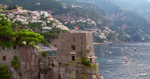 Discovering Positano village aerial shot with boats in sea drone shot