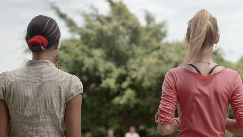 Friends having fun, young men playing sack race in city park with women clapping hands and laughing