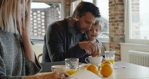 modern family little girl having breakfast with dad while mom uses smartphone and works indoor in modern industrial house. caucasian. 4k handheld slow motion video shot