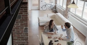 young caucasian couple in love having italian breakfast indoor in modern industrial house. smartphone use. 4k handheld top view overhead video shot