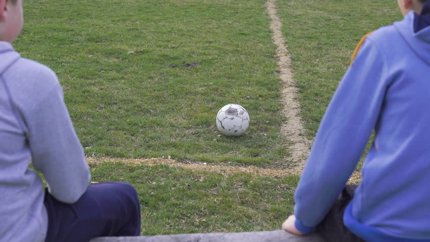 Back look of boys siitting on the bench on the stadium in 4K