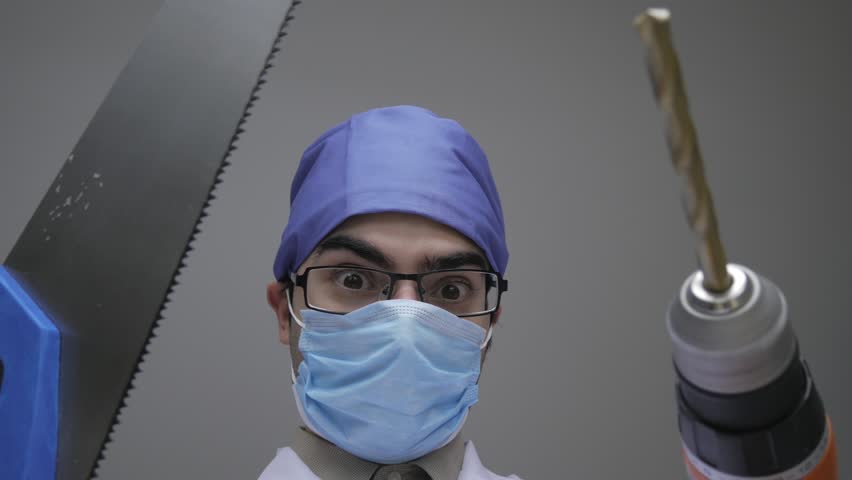 Dentist holding a wood saw and a construction drill while looking scary and dangerous. Personal or patient mouth point of view POV. Royalty-Free Stock Footage #25660172