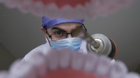 Dentist holding a construction drill while looking scary and dangerous. Personal or patient mouth point of view POV.