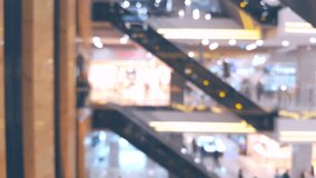 Shopping mall with many people on escalators, blurred defocused background
