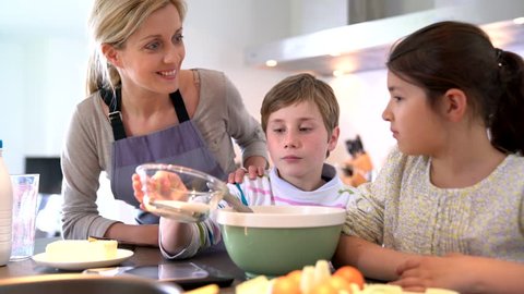 Mommy with kids baking cake together in home kitchen