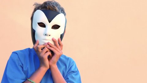 Little boy holds two masks near faces and then removes them one for another