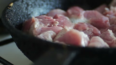 Shot of a meat cooking in the frying pan. Man is stirring it with a turner.Pieces of Juicy fresh meat in a frying pan.