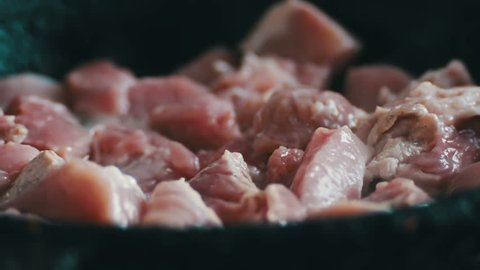 Pieces of meat with blood and spices are fried in a pan close up view