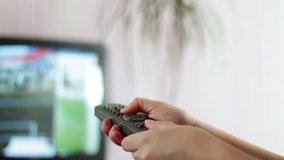 Close up shot of a male hand holding the TV remote control and changing television channels.Switching channels on TV.Hand presses Power Off remote control and switches off TV a close-up shot