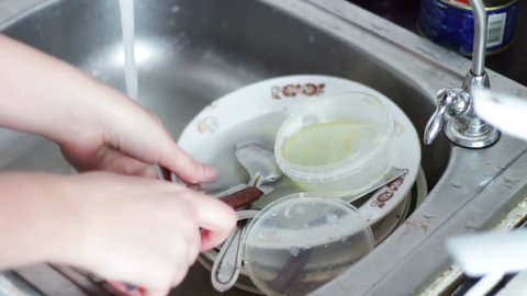 Person cleaning dirty dishes in kitchen close up ,washing dishes in kitchen.Wash out plate under water.