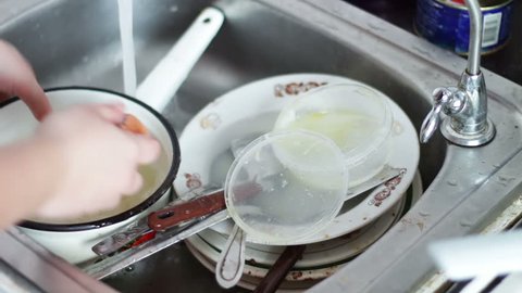 Wash out plate under water. Person cleaning dirty dishes in kitchen close up ,washing dishes in kitchen