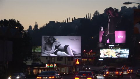 Los Angeles, CA - CIRCA February, 2006: Wide view of billboards in front of a busy highway as seen during dusk
