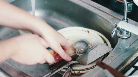 Person cleaning dirty dishes in kitchen close up ,washing dishes in kitchen.Wash out plate under water.