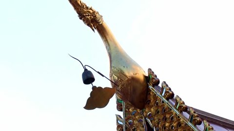 Bell hanging on a decorative roof of a Buddhist pagoda with ornaments.