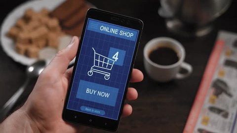Shopping in an online store on your smartphone. The man has already chosen the goods, they are in the virtual basket, the finger presses the button to pay now, the transaction is successful.