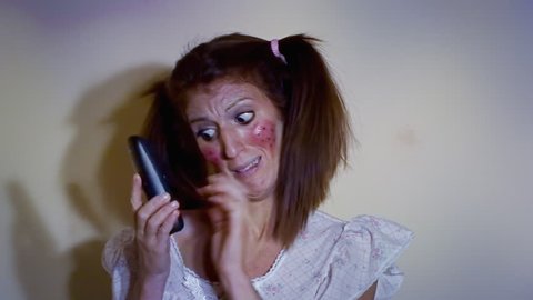 A woman dressed up like a little girl, making a phone call, scared and hiding from a danger we don't see. Funny comedic shot.
