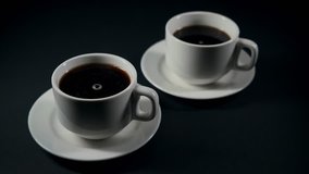 Two steaming cups of black coffee