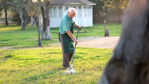 Senior gardener with rake. Old man in apron outdoors. Best gardening tips.