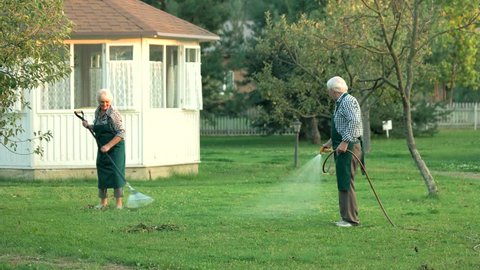 Senior man with garden hose. Gardeners at work.