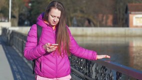 Beautiful young girl in park, on lake, reading message. Go to camera. Pink clothes, springtime, Slow motion. Close up shot