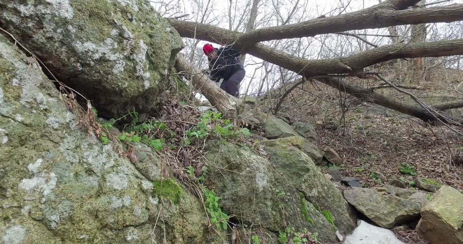 Man and woman tourists go down steep path among rocks in canyon