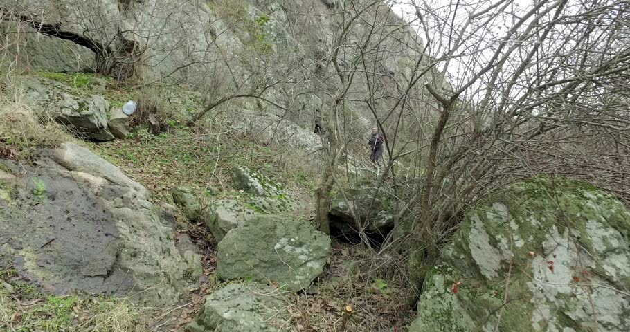 Female tourist descends along steep trail along stones and banks of fast river