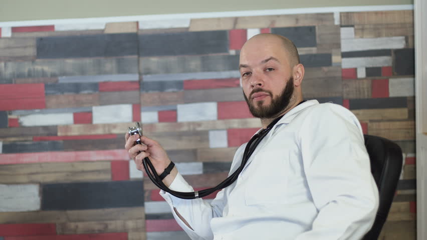 a portrait of a adult 30s bald bearded doctor sitting on his medical room office among table 4k