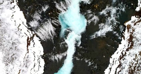 Aerial flight with drone over the famous Bruarfoss waterfall with turquoise water and snow in winter, South Iceland