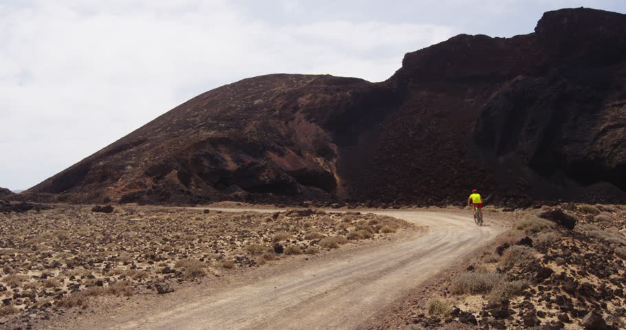 Man mountain biking on MTB bike trail. Man cycling enjoying healthy lifetyle and outdoor sports actvity. Lanzarote, Canary Islands, Spain. RED EPIC SLOW MOTION.