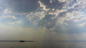 Sun rays through the clouds. A river landscape. Spring. Ice drift on the river. Russia, Saratov, the Volga river. Time-lapse recording. Footage in 4K, UHD.