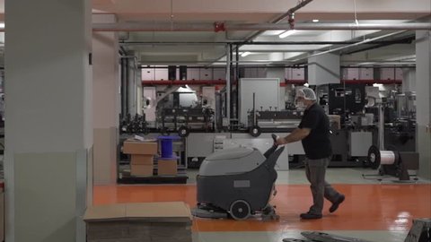 Corona Worker Man With a Floor Cleaner Machine in the  Factory Passing by During Covid Outbreak