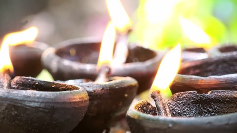 Close up follow focus video of burning oil lamps and incense joss sticks at temple. Traditional offering in buddhist and hindu temples
