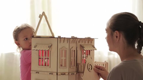Young woman building dollhouse for her little daughter, indoor